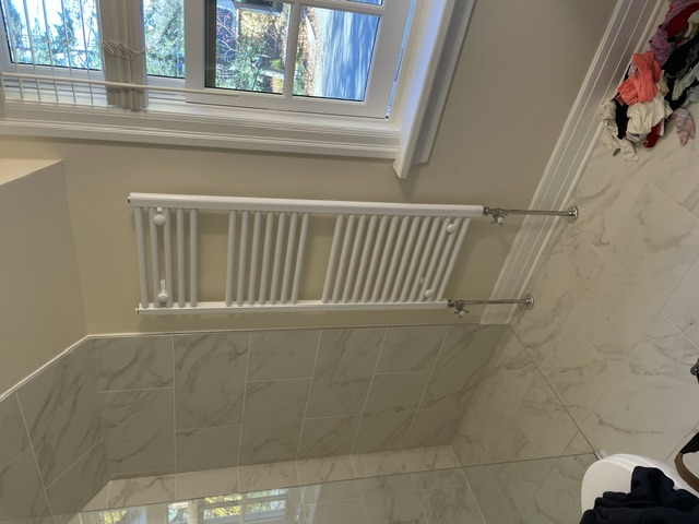 Wall-mounted towel warmer radiator in a bathroom.